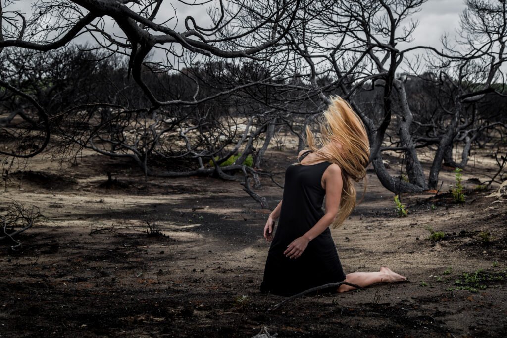femme sans visage pour exprimer la perte d'identité dans un paysage d'arbres morts.
