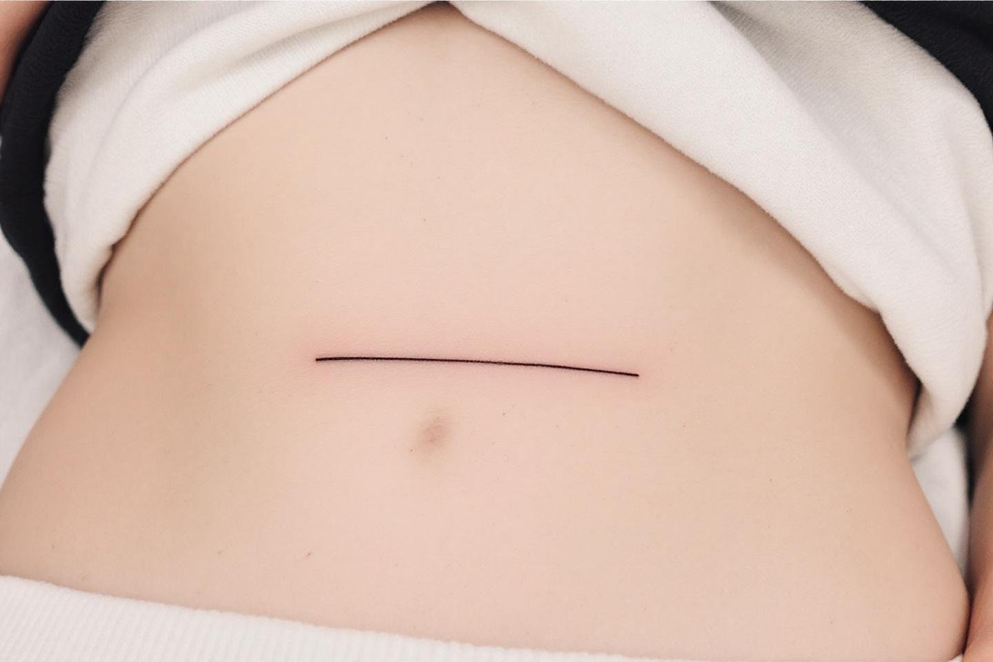 Ligne horizontale fine sur peau claire, entourée de tissu blanc
