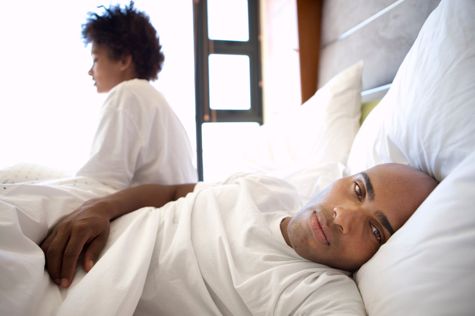 couple au lit , homme tourné de son coté semble préocupé . suggestion de problème sexuel