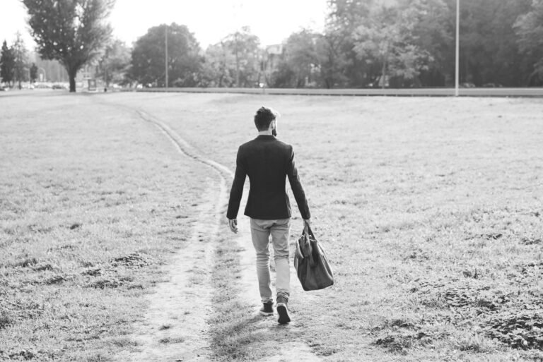 jeune homme vue de dos partant sur un chemin un sac à la main